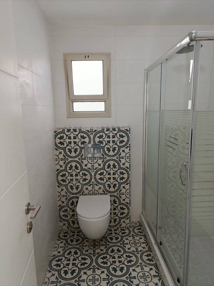 שירותים במבנה יביל — אסלה תלויה, חיפוי קיר מעוטר ומקלחון